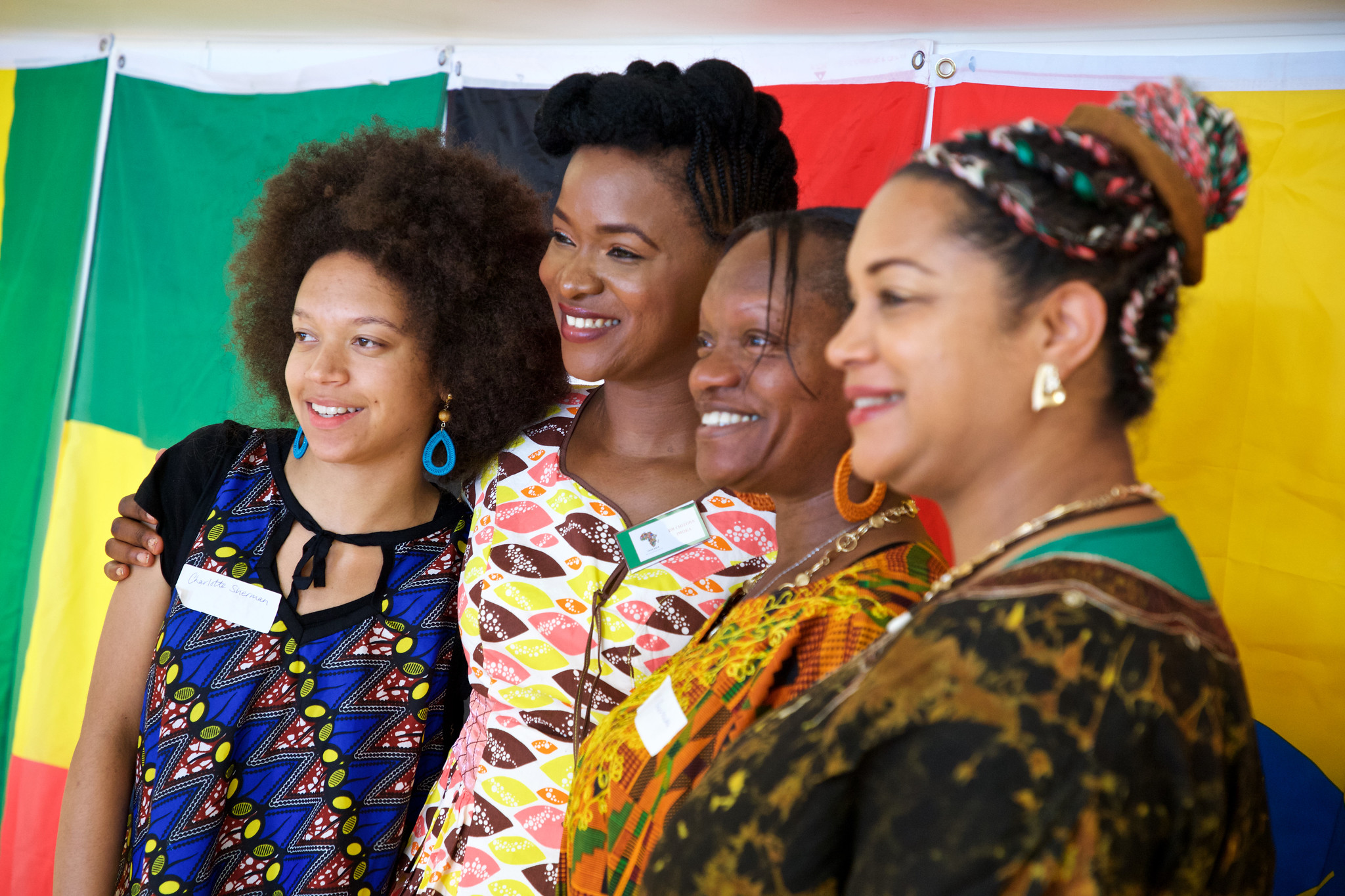 Four attendants to the 2019 Forever Africa Conference and Events (FACE) event pose for a photo in front of a backdrop of African flags.